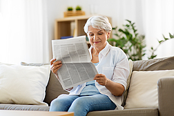 senior woman reading newspaper at home