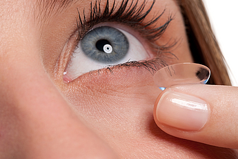 Close-up of blue woman eye with contact lens applying