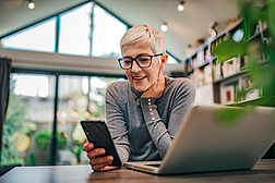 Portrait of a cheerful senior businesswoman using smart phone at home office, close-up.