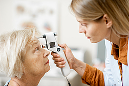 Ophthalmologist measuring eye pressure to a senior woman