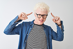 Young albino blond man wearing denim shirt and glasses over isolated white background smiling pointing to head with both hands finger, great idea or thought, good memory